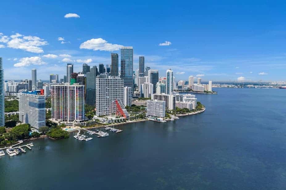 Miami skyline with high-rise buildings, residential towers, and a bay under partly cloudy skies