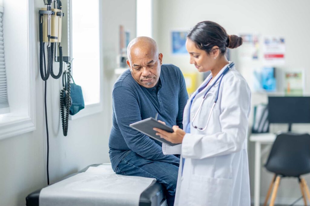 Doctor reviewing information on a tablet with a patient in an exam room