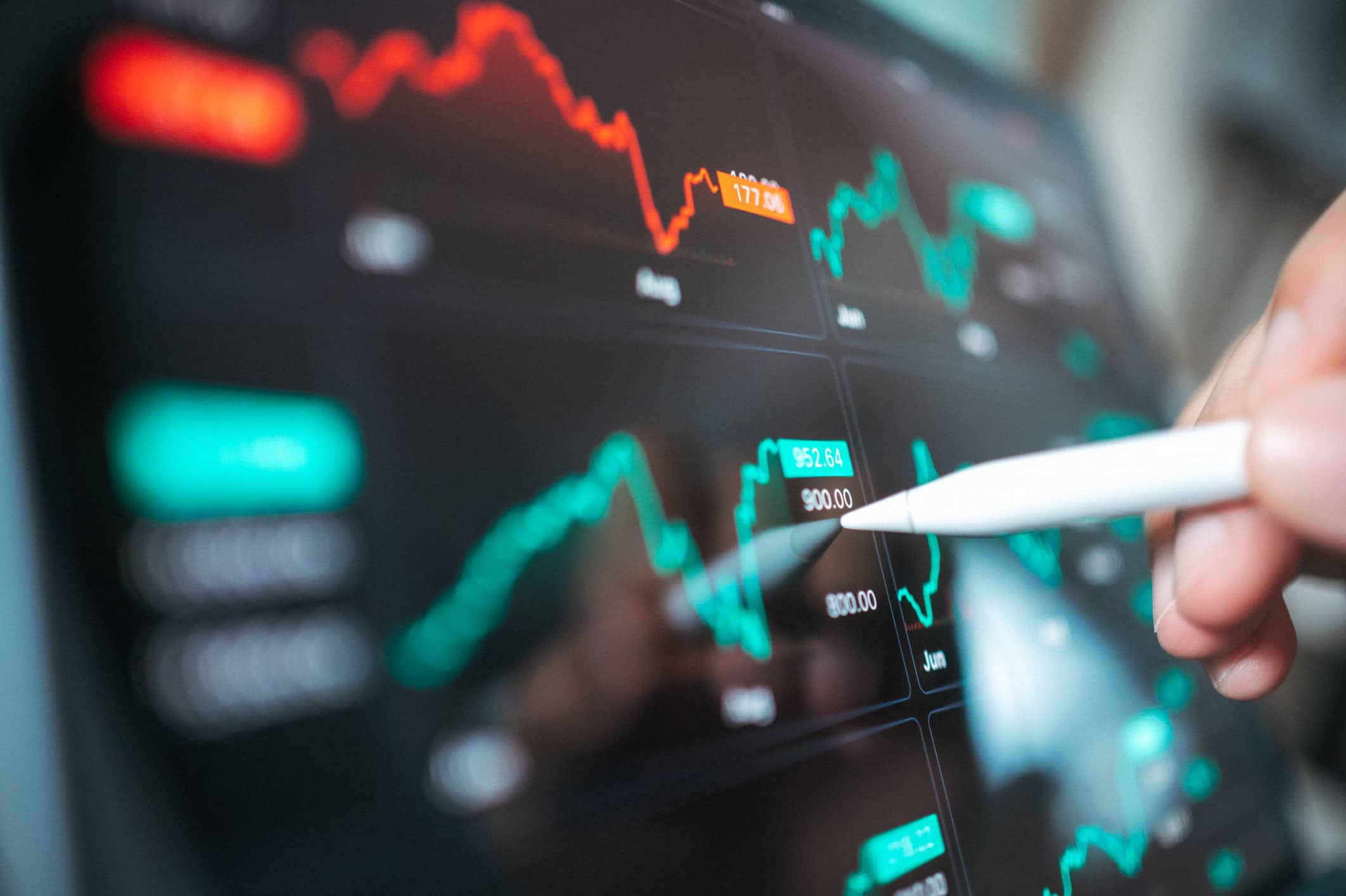 Stylus interacting with a digital screen showing financial charts and market trends