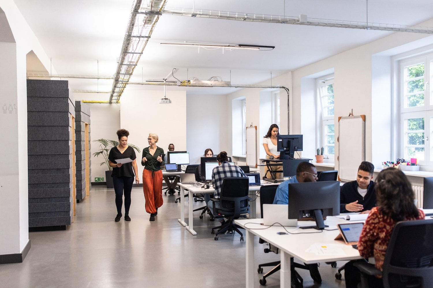 Open-plan office with employees working at desks while colleagues walk through the workspace