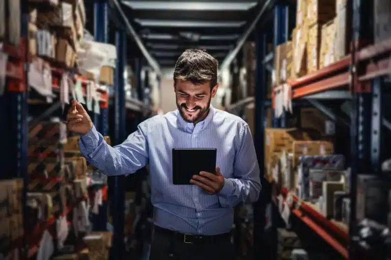 Warehouse manager using tablet in storage aisle