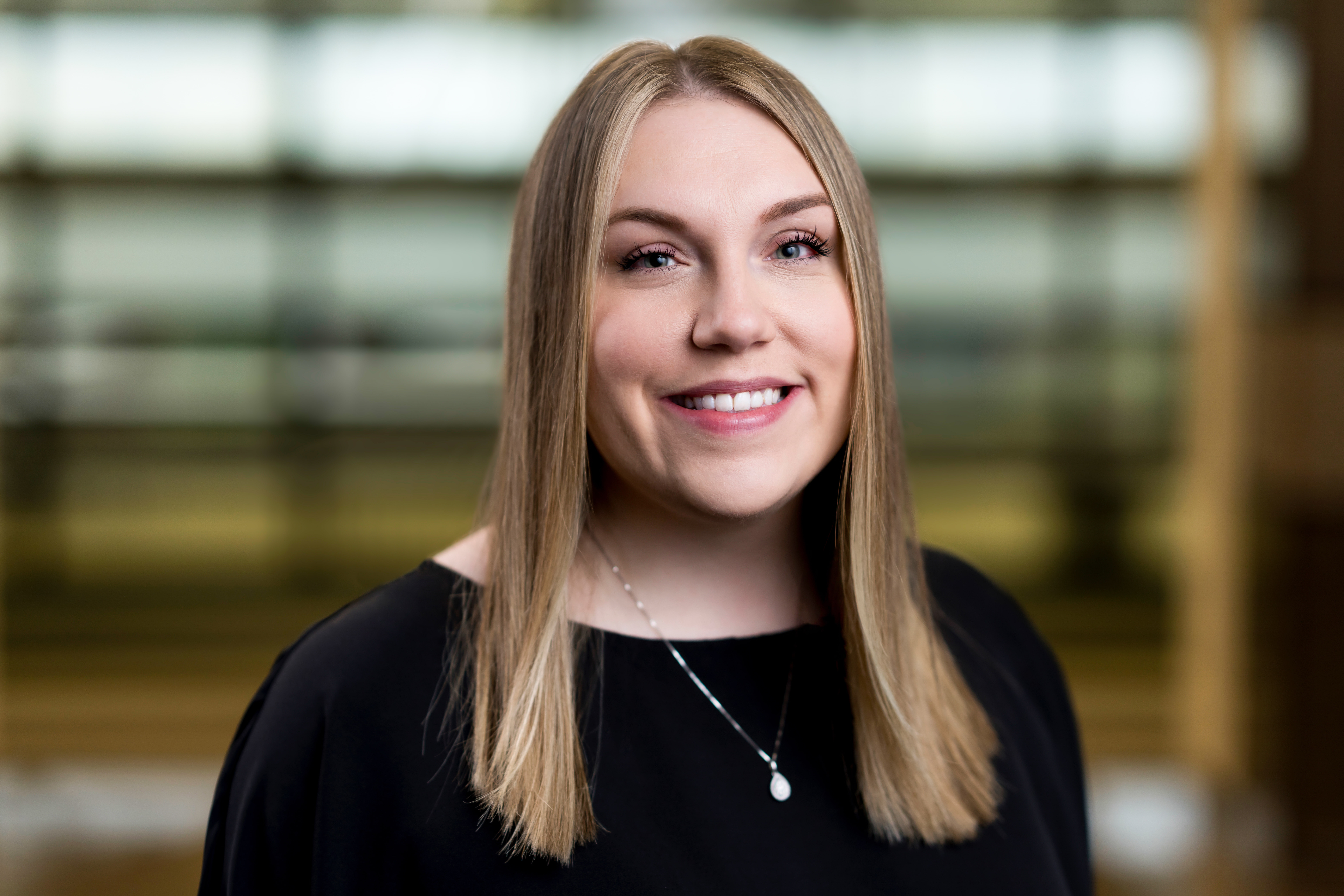 Professional headshot of Caitlin Fulmer wearing a white shirt and dark blazer in an office setting