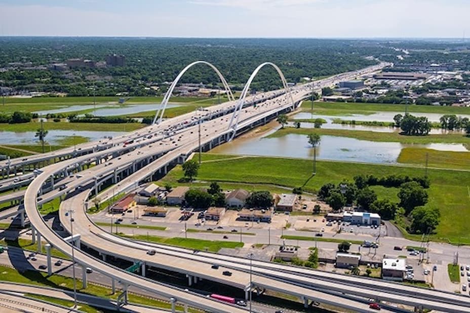 Arched highway bridge carrying traffic over a green landscape and waterways