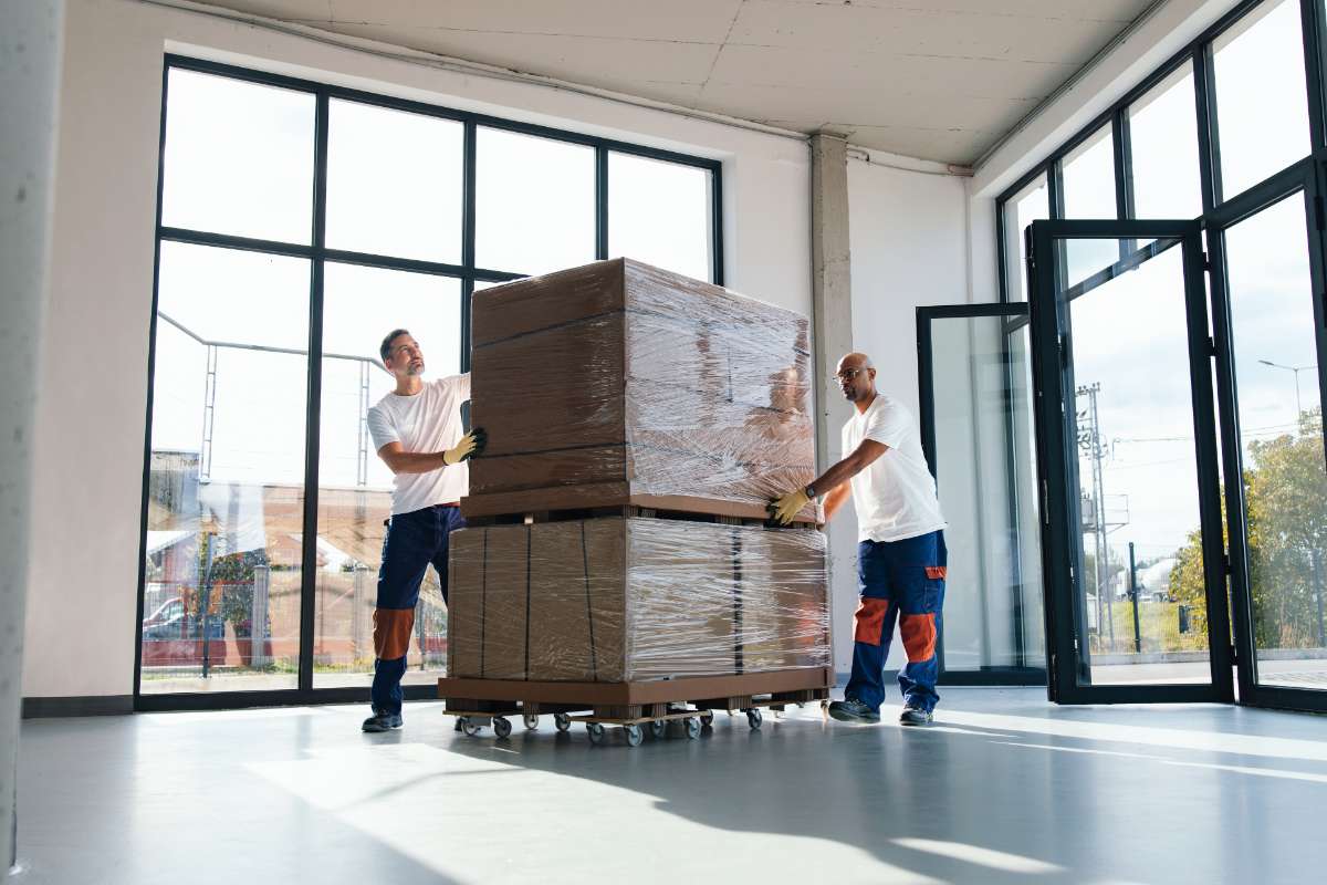 Movers carrying stacked boxes into a modern home