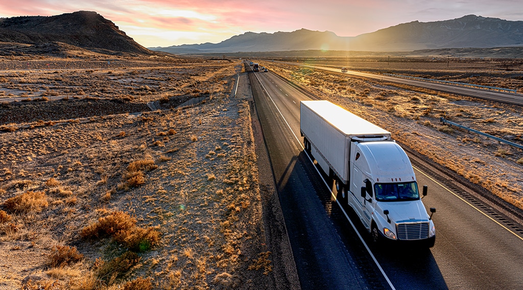 Truck driving on a highway at sunset